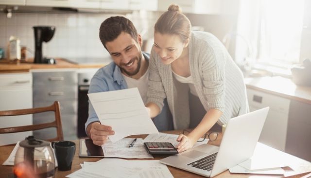 front view of a man and a woman reviewing finances and shopping for mattresses online smiling