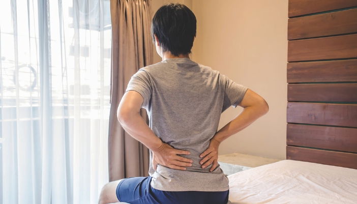 Man holding his lower back because his bed caused him pain