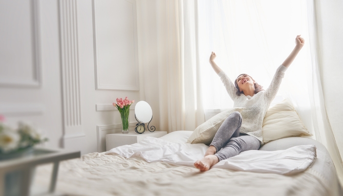 Woman waking up bright and enjoying the comfort of her bed