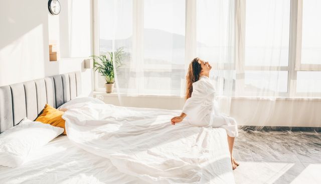view of a woman peacefully waking up and smiling on a large white bed