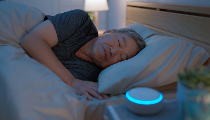 An senior Asian man sleeping next to his bedside sleep tracker