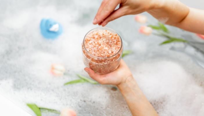 Closeup of someone adding homemade bath salts to their bath