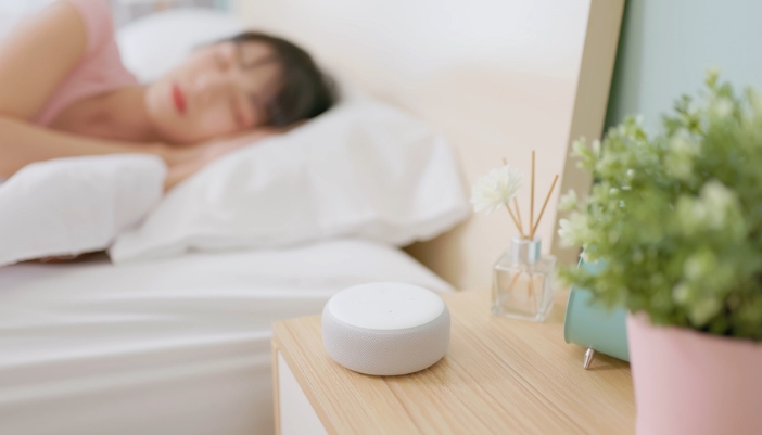 A woman sleeping with a reed diffuser next to her on her nightstand