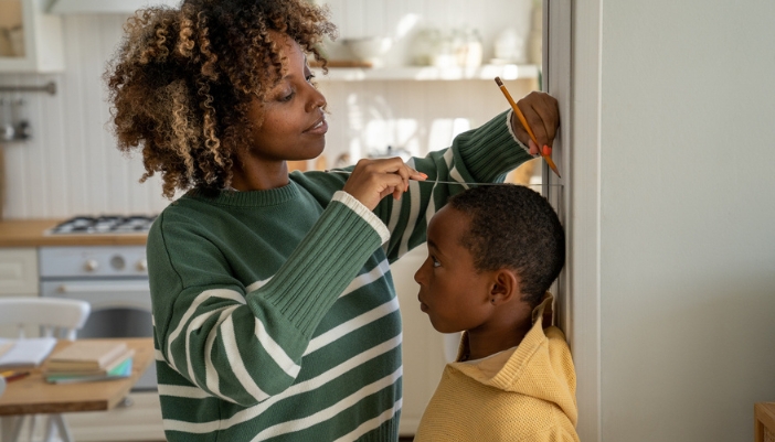 Mom measuring her son’s heigh on a wall after growth spurt