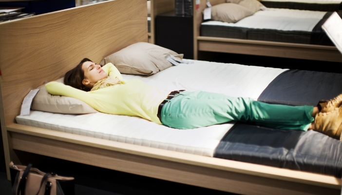A woman lying on the bed is assessing how she feels on a mattress