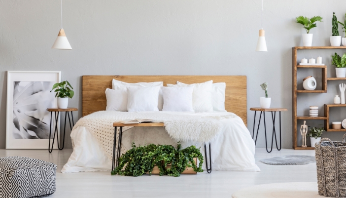 A clean, brightly lit bedroom with a bed with white sheets/pillows perfectly made.