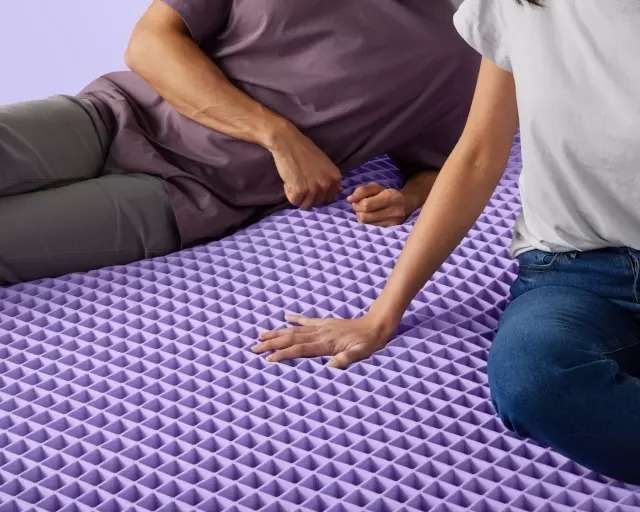 view of a couple sitting on a purple grid mattress