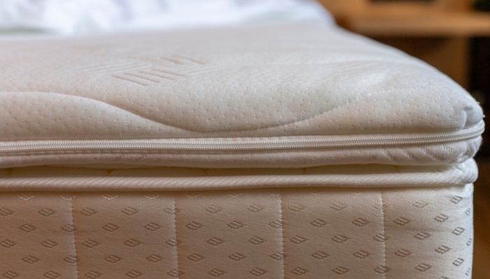  A padded mattress sits in a warmly lit bedroom with no sheets or pillows.