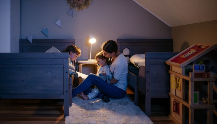 A mom reads a book to two young children for bedtime. 