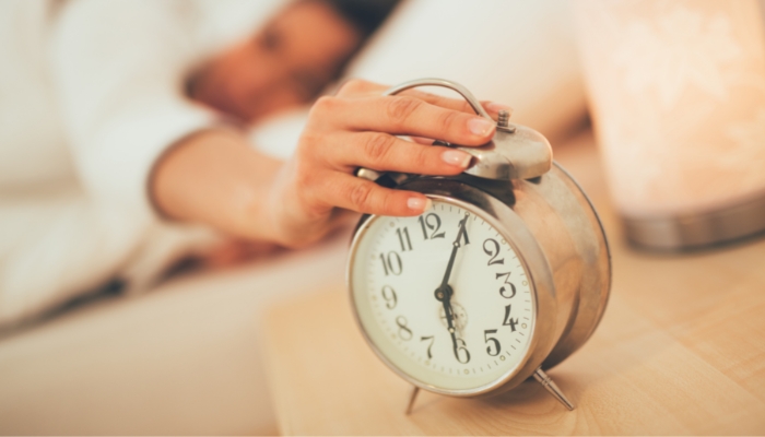 woman reaching to turn off alarm clock 