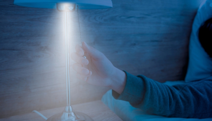 close up of arm reaching to turn lamp off in a darkened room