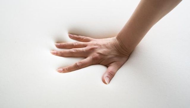 hand pressing onto memory foam mattress