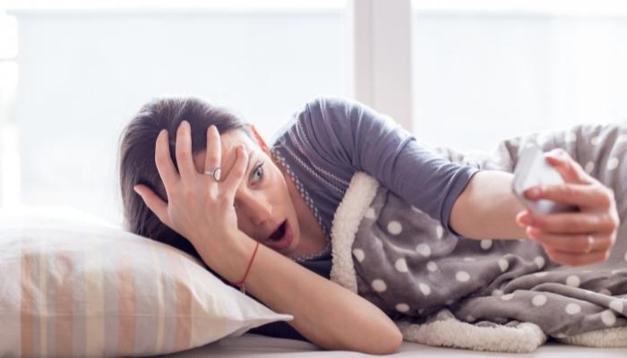 Woman looking at her alarm, realizing she overslept