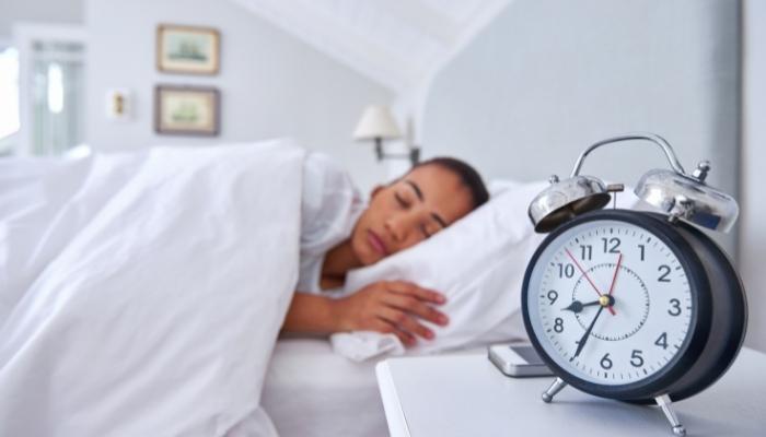 Woman sleeping peacefully next to clock