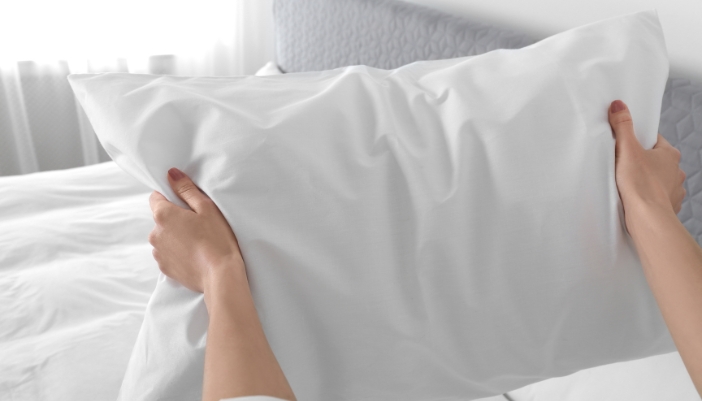 Closeup of someone fluffing their pillow
