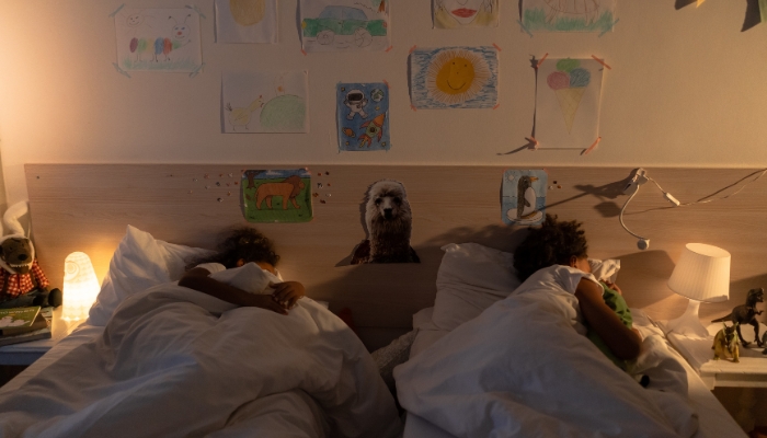 Two young tweens sleeping in twin beds side by side