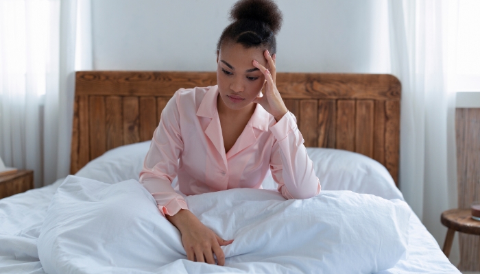 Woman clutching her head and is too stressed to sleep