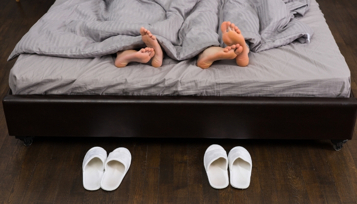 Two pairs of slippers facing the bed while a couple sleeps; bad omens