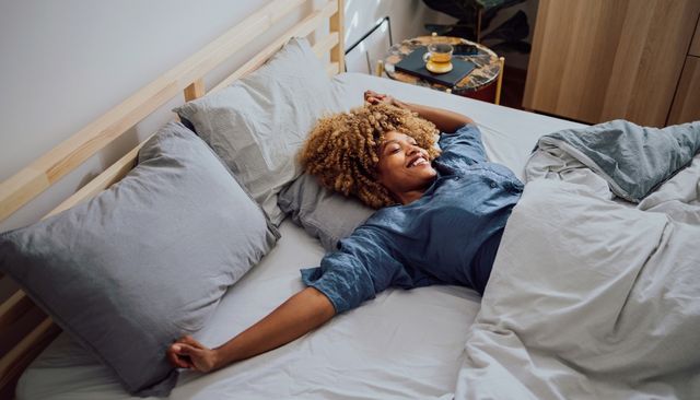 front view of a woman waking up, stretching, and smiling on a medium firm mattress