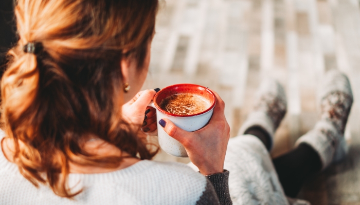 The back of a woman's head is featured as she drinks coffee.