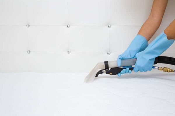 view of a person using a vacuum on a mattress