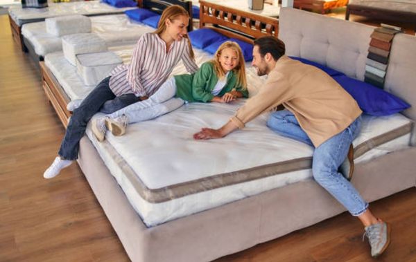 front view of a family sitting on and testing a mattress in a mattress store