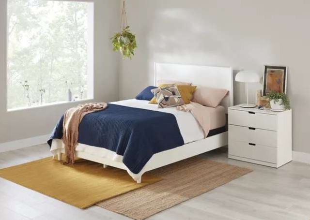 view of a bed in a minimal white modern bedroom with a navy blue comforter