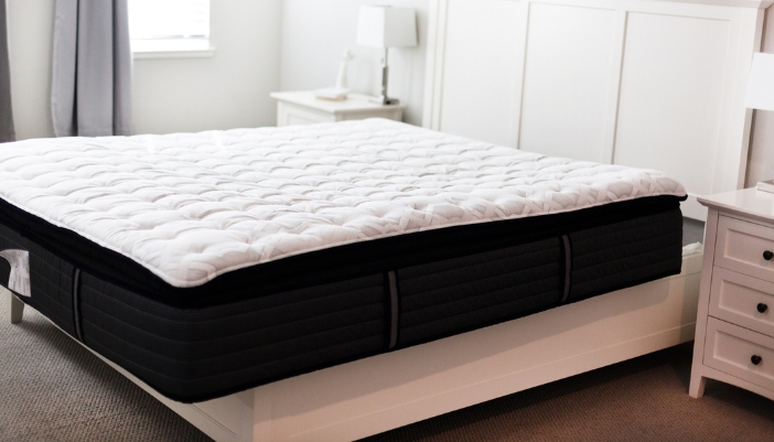 A new pillow top mattress on a white bed frame