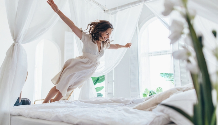 A woman falls into a fresh, clean made bed.