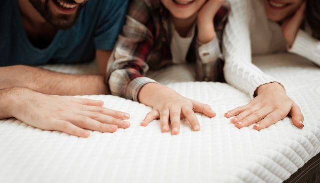 front view of a family feeling the top of a hybrid mattress