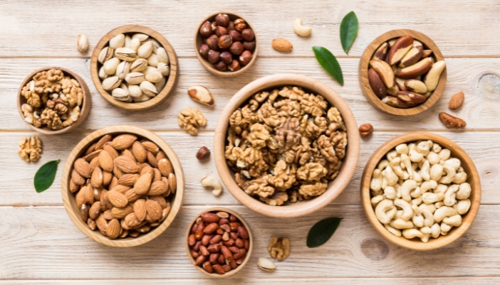 Wooden bowls with nuts on a wooden plank table.