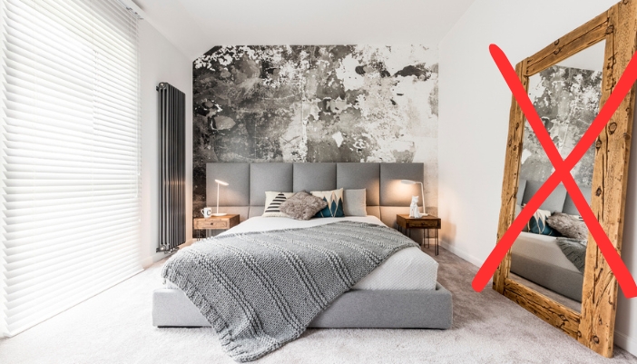 A modern bedroom featuring a mirror with a big “X” over it.