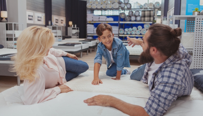 A man, woman, and child test out a mattress in a showroom.