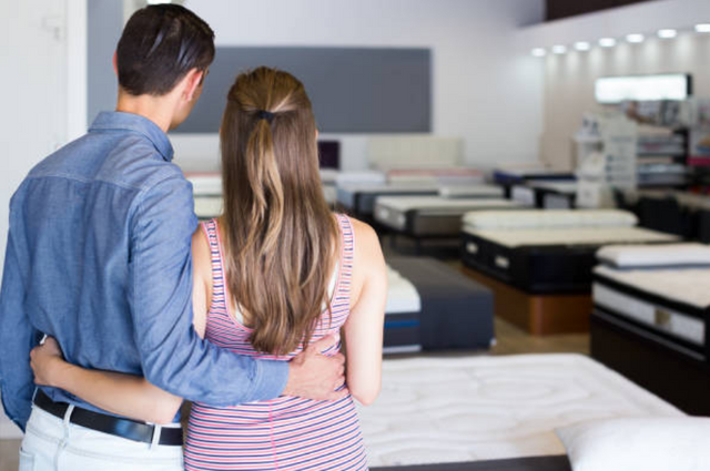 view from behind of a couple looking across a mattress store 