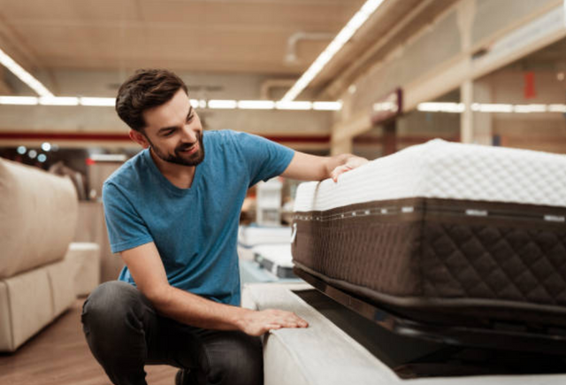 front view of a man examining a mattress in a mattress store