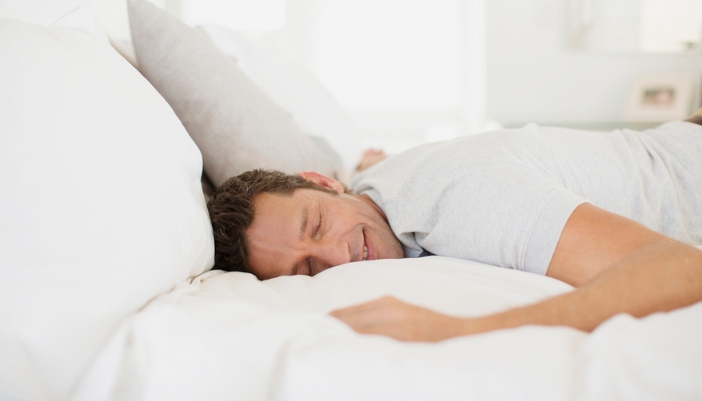 A man lays on his stomach and sleeps soundly.