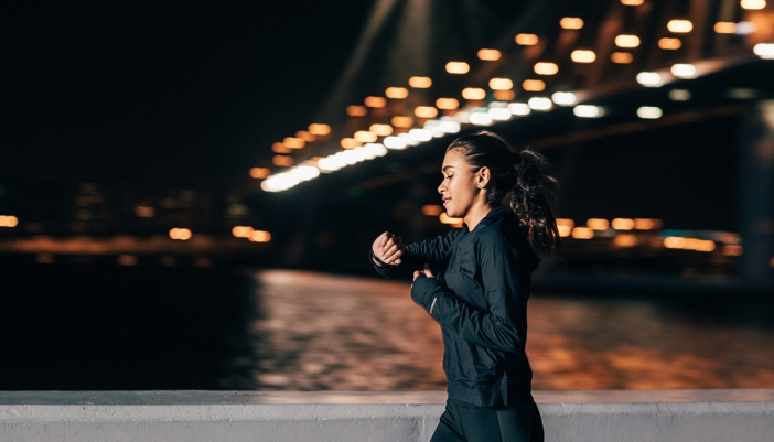 A woman goes for a run in a city at night.