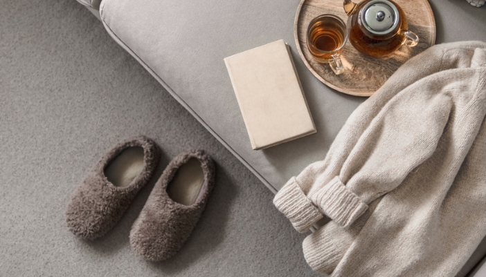 A cozy setup of a pair of slippers, sweater, and nighttime tea. 