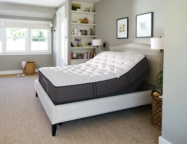 The Sealy Ease adjustable bed and headboard in a bedroom 