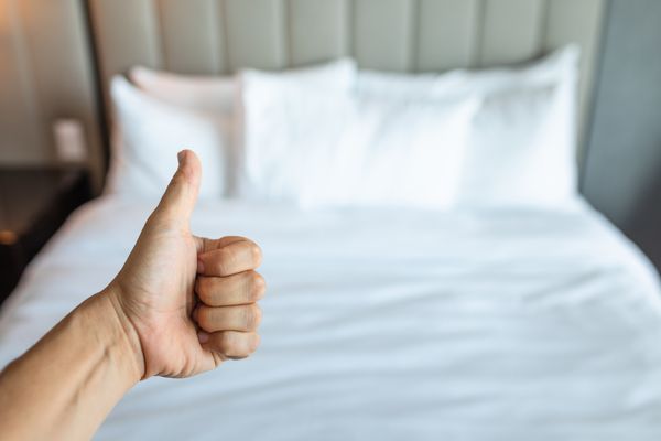 A person giving a thumbs-up in front of a mattress