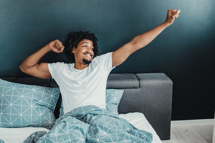 Young man in the morning waking up and stretching.