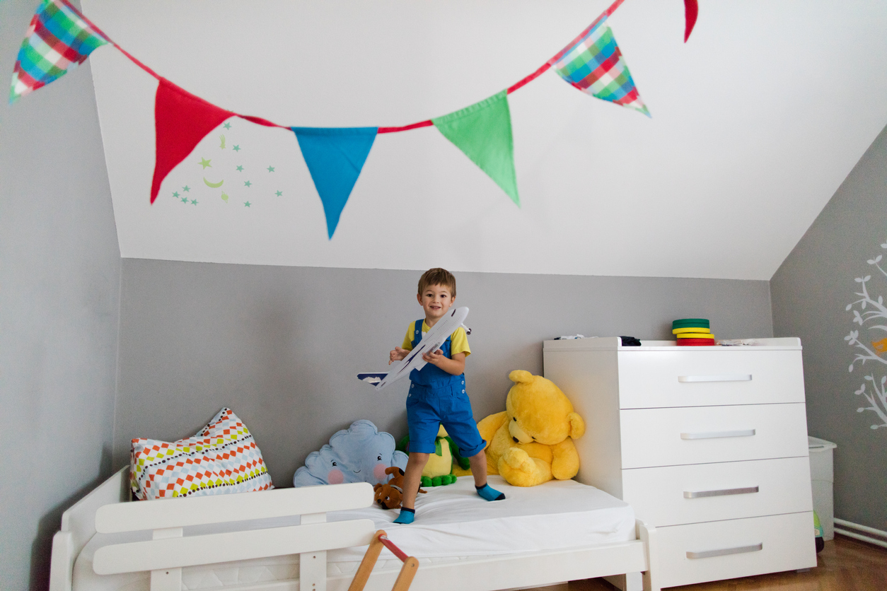 little boy playing with a toy plane in his new bed
