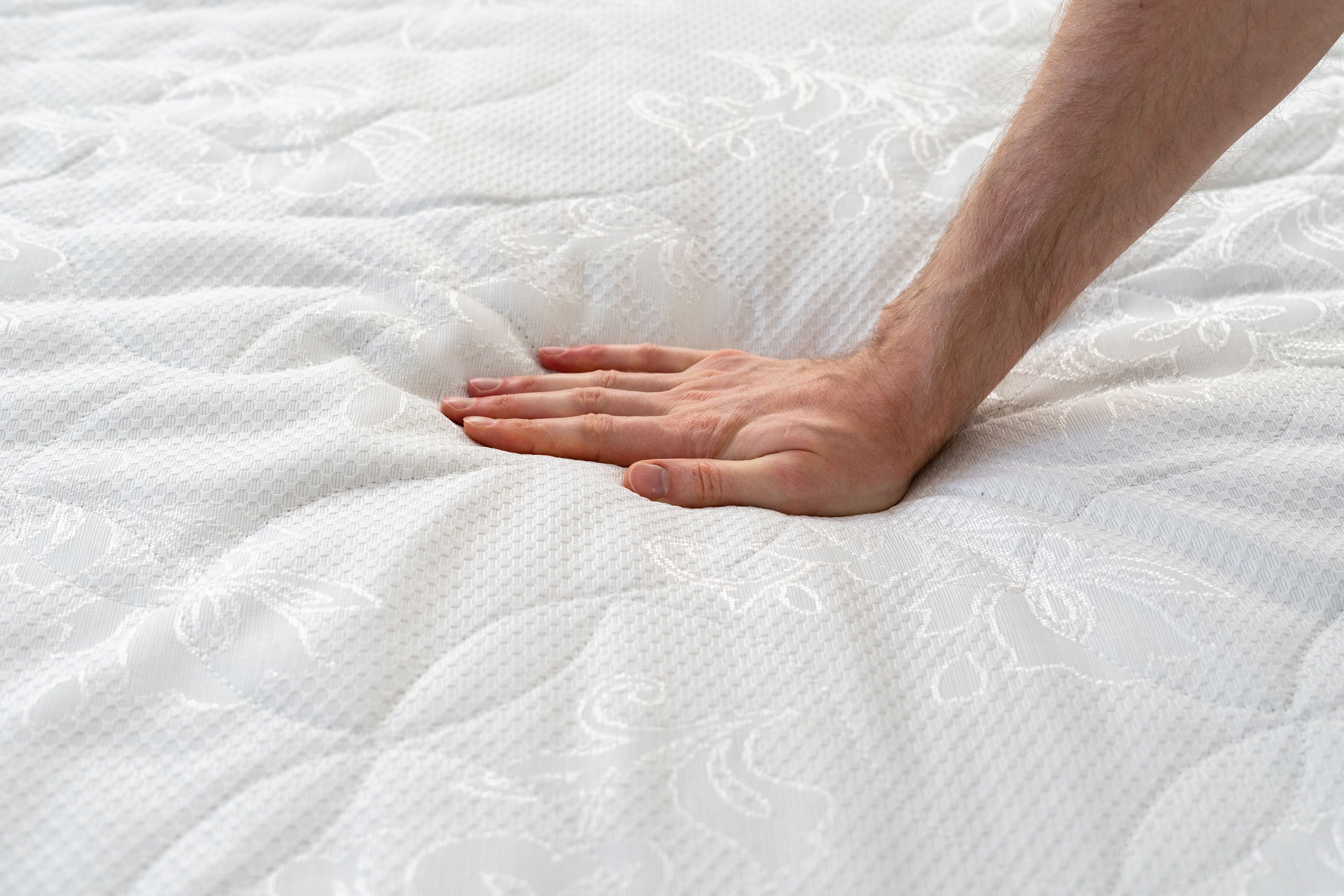 Person pressing down on a mattress topper 