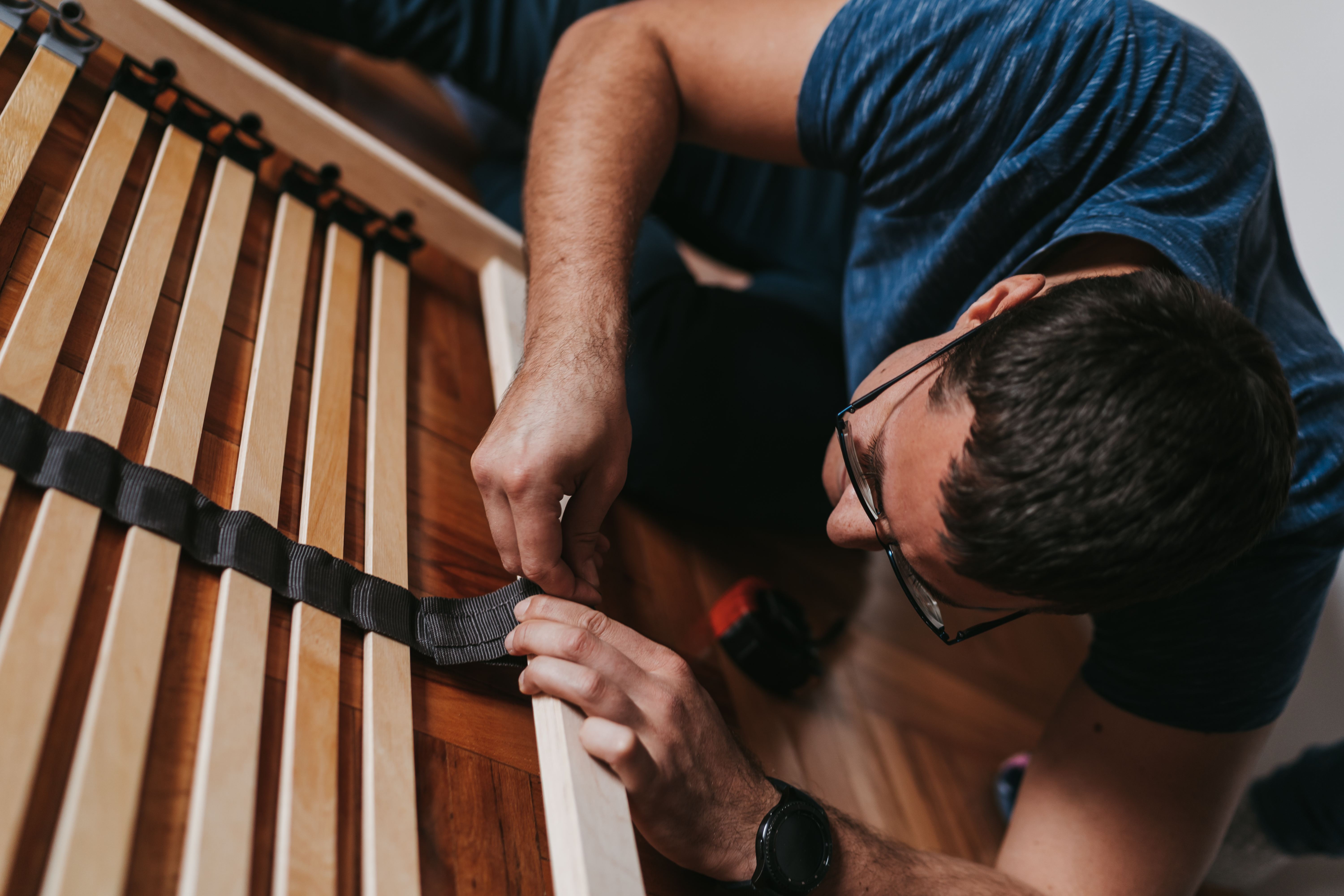 A man installing slats on a mattress foundation 