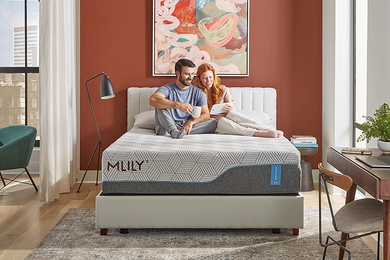A couple smiling while sitting on top of an MLIL mattress 