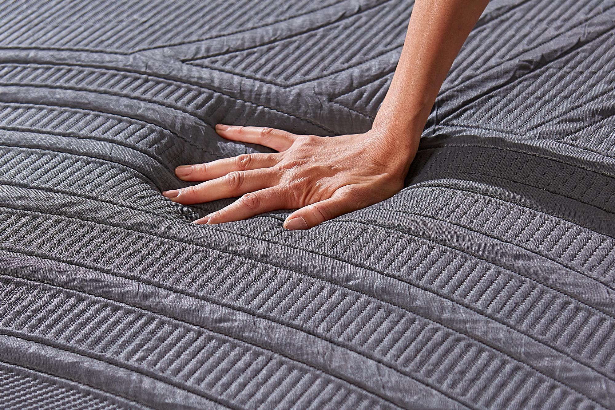 A person pressing down on the Cooling Knit Fabric Cover of an MLILY mattress 