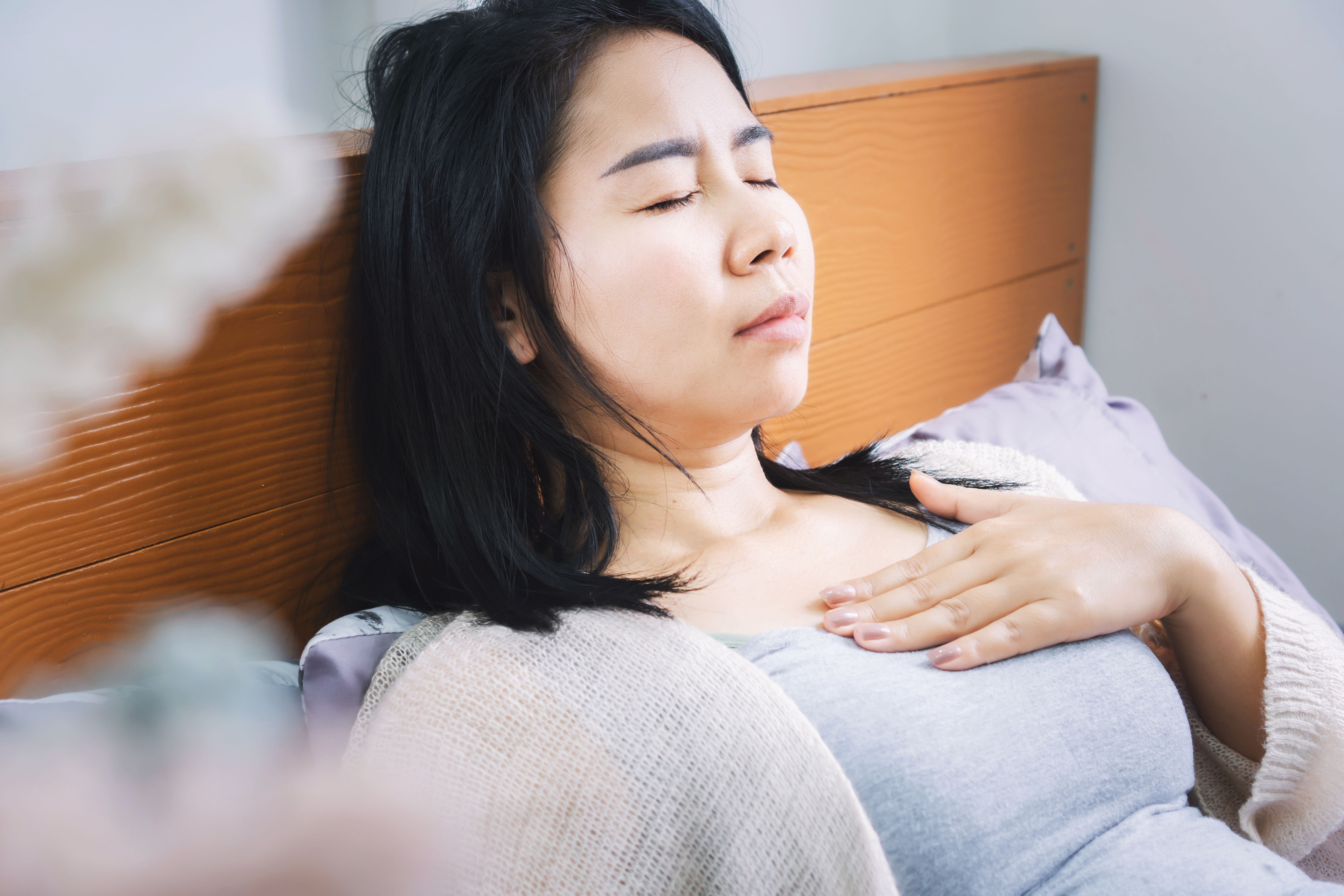 A young woman suffering from acid reflux in bed 