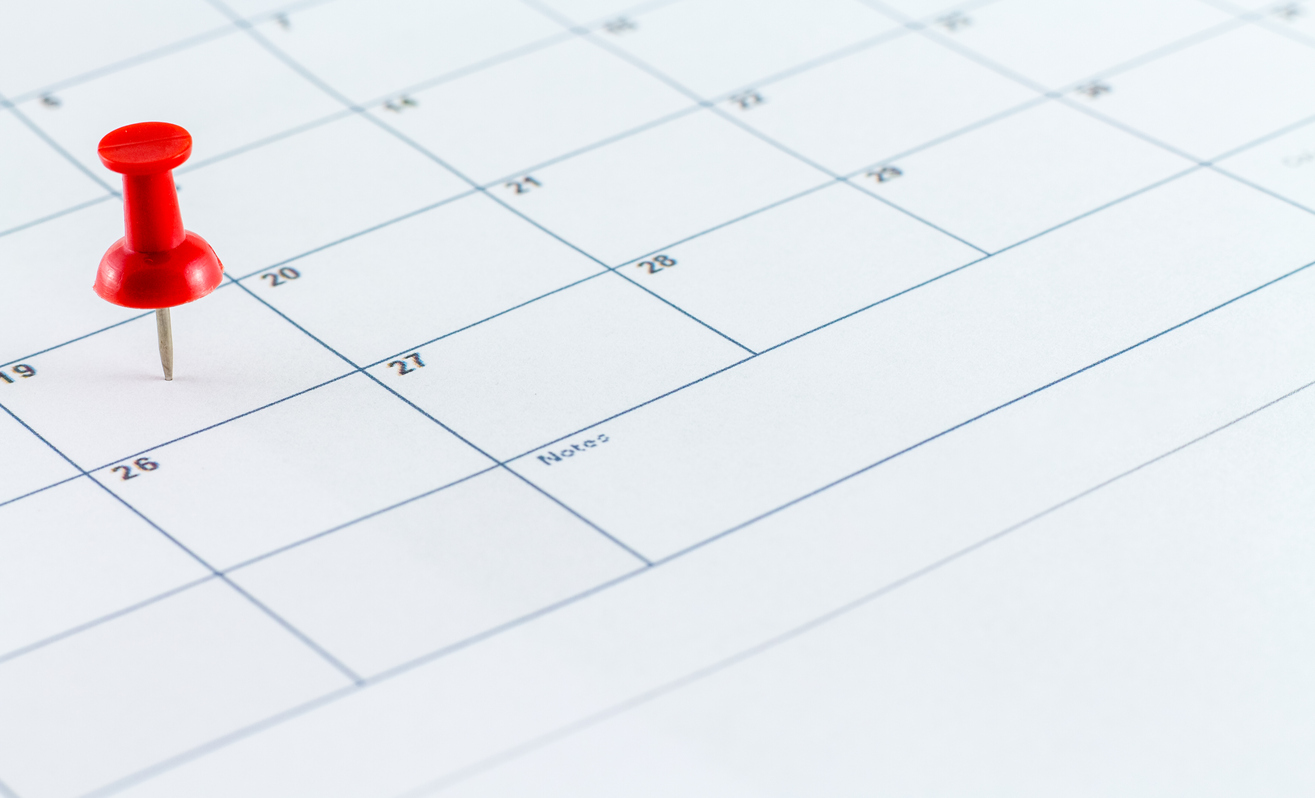 A red thumbtack on a calendar 