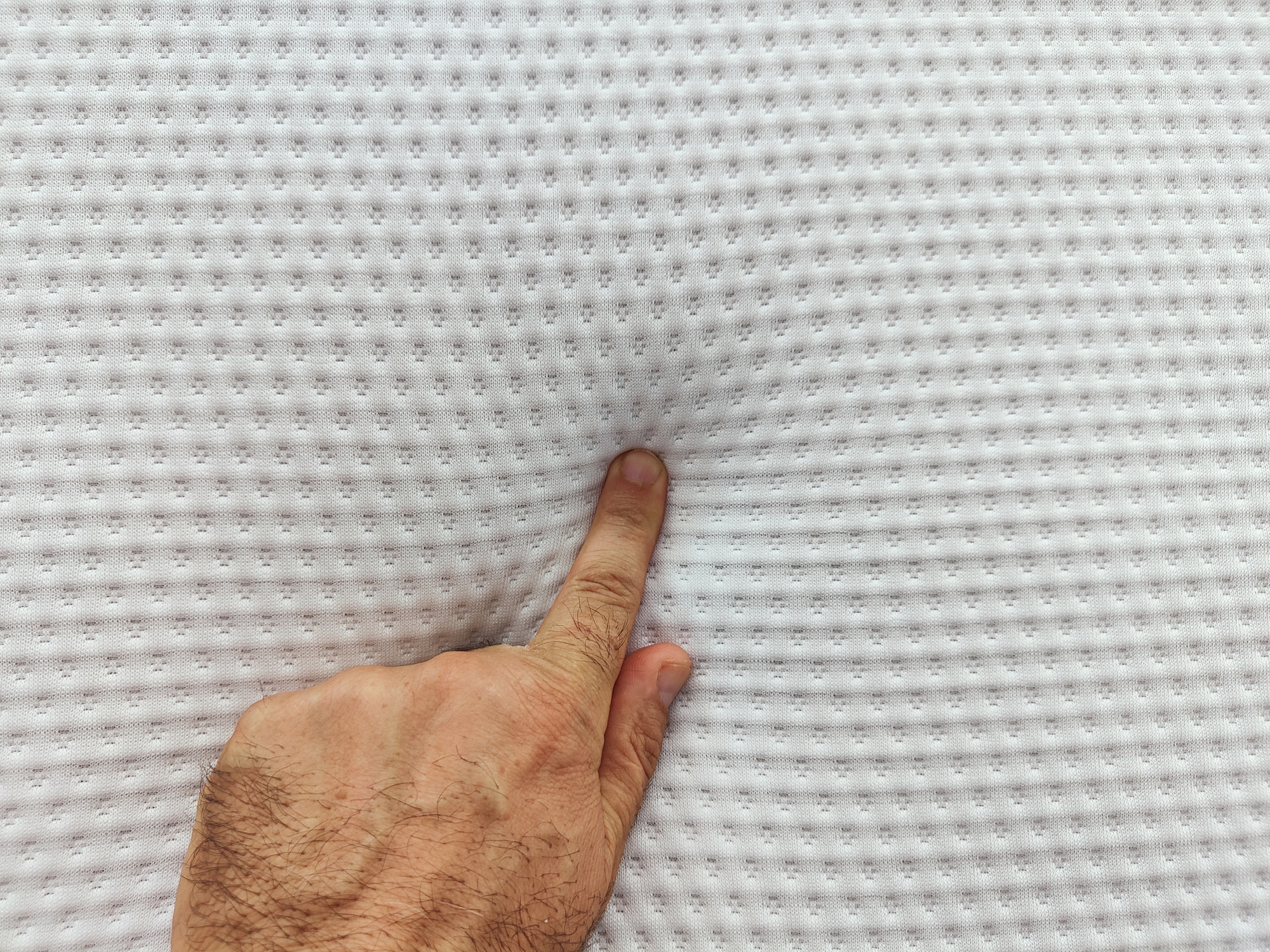 A person pressing down on a memory foam mattress