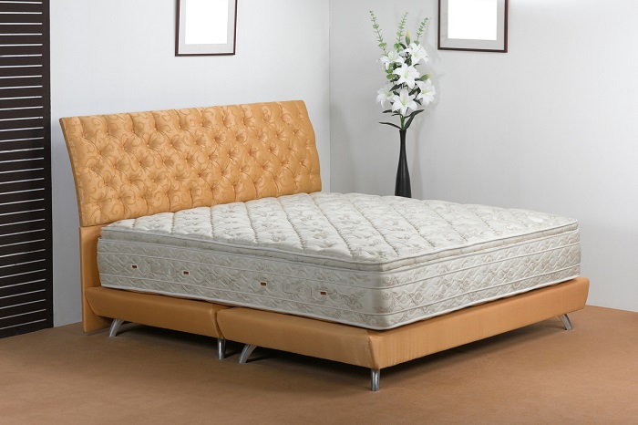 Modern bedroom with innerspring mattress on a tan leather bedframe with headboard. 